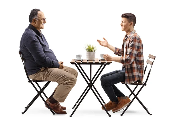 一个年轻人和一个成熟的男人交谈 坐在一间被白色背景隔离的咖啡馆里 — 图库照片