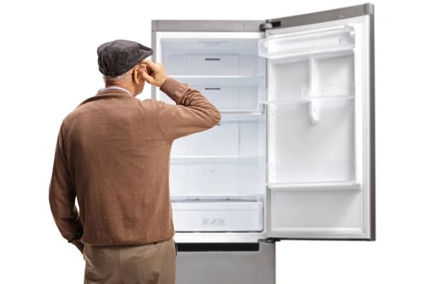 白い背景に隔離された空の冷蔵庫の前に立っている老人の後部ビューショット — ストック写真