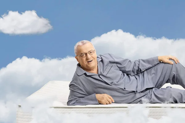 Mature Man Pajamas Lying Mattress Floating Sky Clouds — Stock Photo, Image