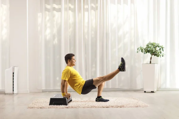 男人在地毯上的房间里的台阶有氧平台上锻炼 — 图库照片