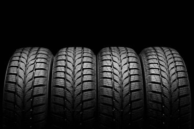 Siyah arka planda dört araba lastiği var.