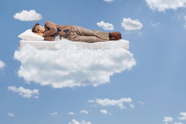 Yaşlı adam bir direğin üzerinde uyuyor ve bulutlarla mavi bir gökyüzünde yüzüyor.