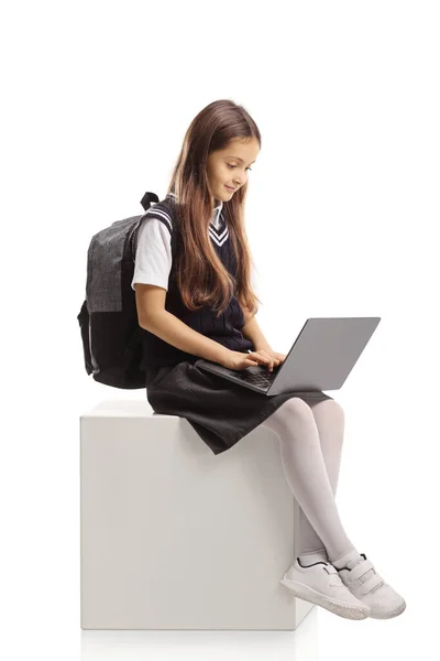 Schoolmeisje Met Een Laptop Computer Zittend Een Witte Kubus Geïsoleerd — Stockfoto