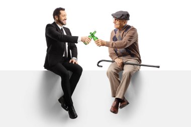 Yaşlı bir adam ve bir iş adamı boş bir panelde oturup beyaz arka planda izole edilmiş birayla kadeh kaldırıyorlar.