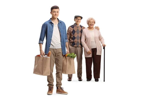 若い男を助ける高齢者のカップルと運ぶ食料品袋白い背景に隔離された — ストック写真