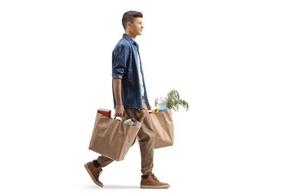 フル長さプロフィールショットの男を運ぶ食料品袋と歩行孤立した上に白い背景 — ストック写真