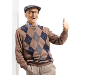 Duvara yaslanan ve beyaz arka planda izole edilmiş baş parmaklarını gösteren yaşlı bir beyefendi.