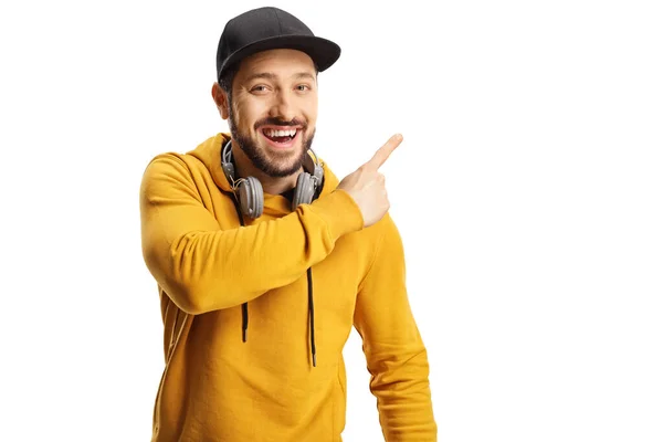 Cheerful Guy Headphones Cap Pointing Side Isolated White Background — Stockfoto