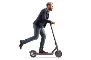Full length profile shot of a young man in suit and jeans riding an electric scooter isolated on white background