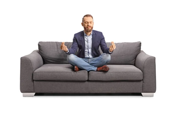 若いです男瞑想上のソファ隔離された白い背景 — ストック写真