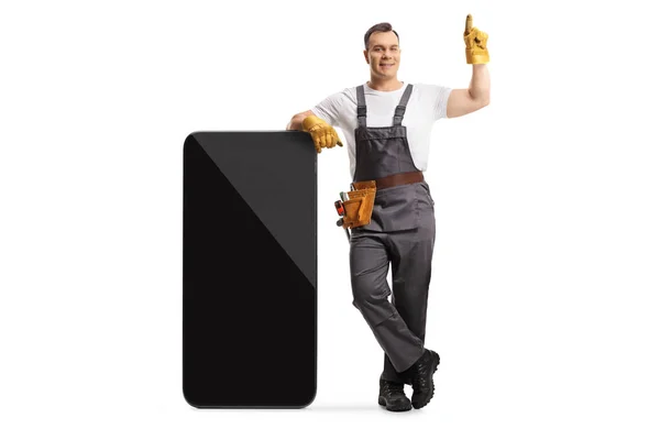 Full Length Portrait Repairman Uniform Leaning Big Smartphone Pointing Isolated — Stock Photo, Image