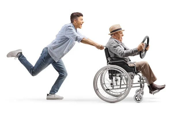 Full Length Profile Shot Young Man Running Pushing Elderly Man — Φωτογραφία Αρχείου