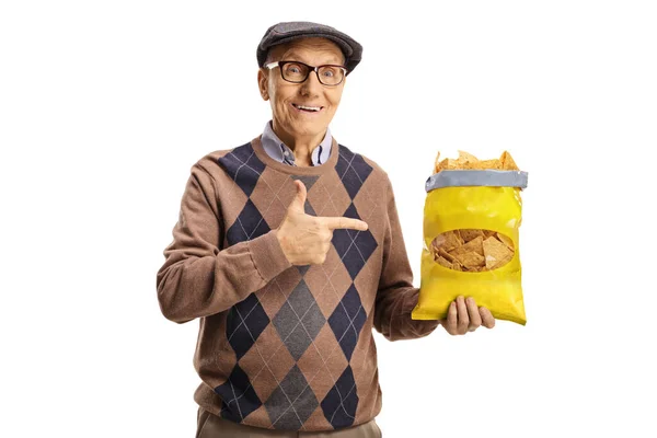 Χαρούμενος Ηλικιωμένος Που Κρατάει Ένα Πακέτο Πατατάκια Και Δείχνει Απομονωμένος — Φωτογραφία Αρχείου