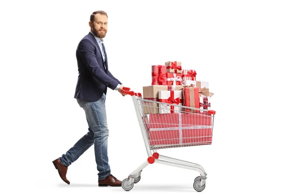 白い背景に隔離されたショッピングカートでプレゼントと一緒に歩く男の完全な長さのショット — ストック写真