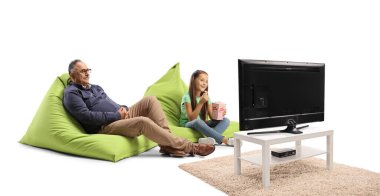 Büyükbaba ve torun fasulye çuvalında oturuyorlar ve beyaz arka planda izole televizyon izliyorlar.