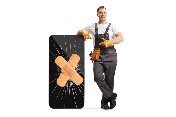 Full Length Portrait Repairman Leaning Broken Mobile Phone Bandage Pointing — Stock Photo, Image