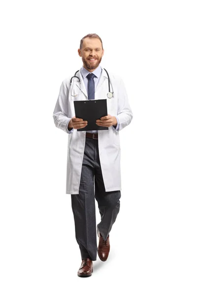 笑顔の若い男性医師の完全な長さの肖像画クリップボードを保持し 白い背景に隔離されたカメラに向かって歩く — ストック写真