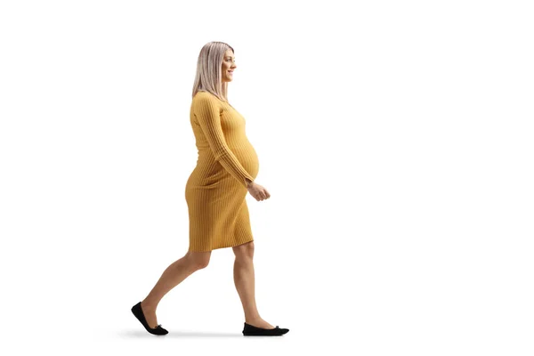 フル長さプロフィールショットの妊娠中の女性でA黄色のドレス歩行隔離された白い背景 — ストック写真