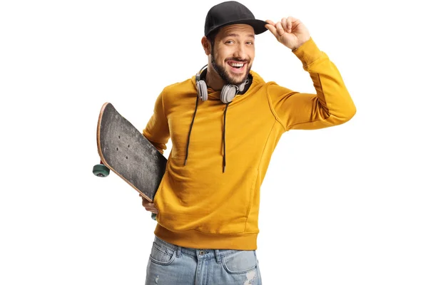 Mladý Muž Sluchátky Drží Skateboard Drží Jeho Čepici Izolované Bílém — Stock fotografie