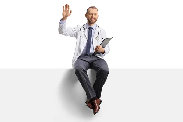 Young Male Doctor Waving Sitting Blank Panel Clipboard His Hands — Stock Photo, Image