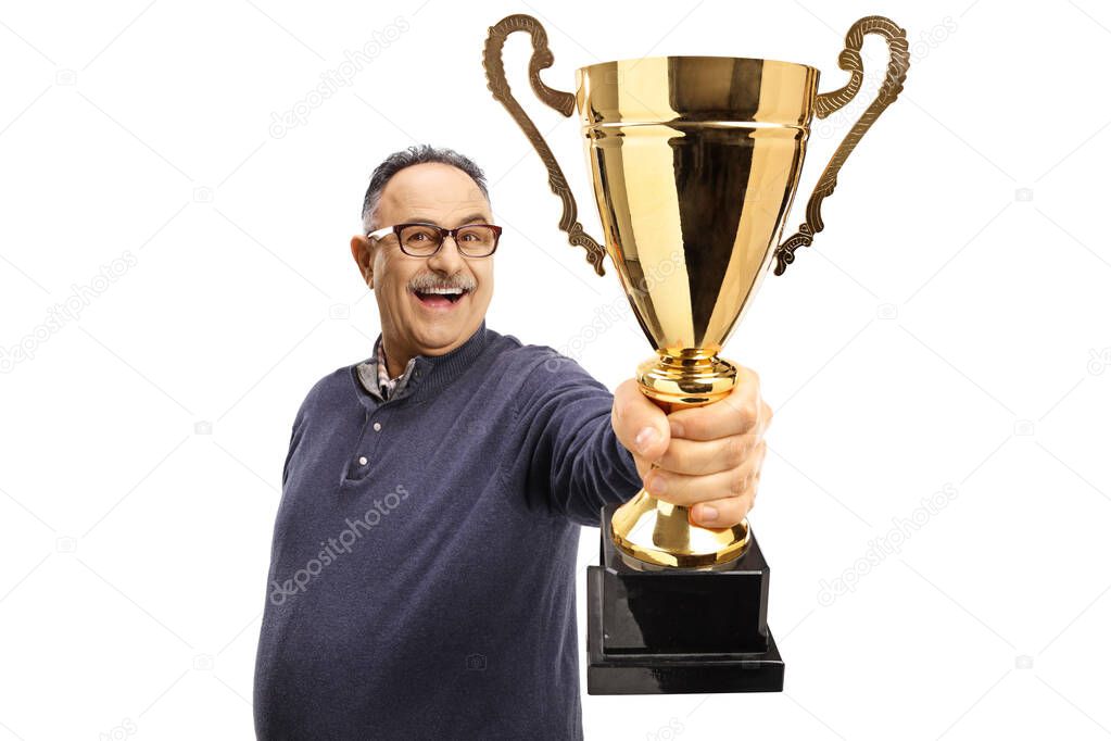 Happy mature man holding a gold trophy cup in front of camera isolated on white background