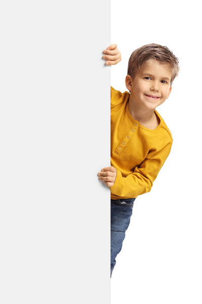 Cute boy peeking from behind a blank white panel isolated on white background