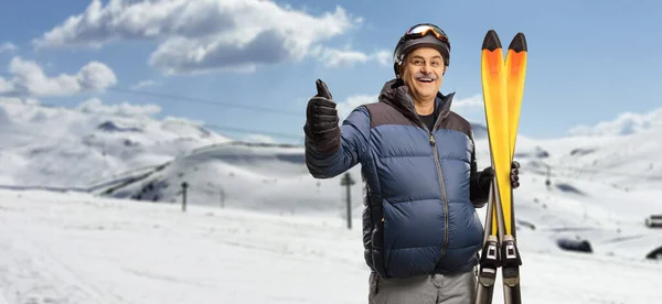 Reifer Mann Hält Ein Paar Skier Und Zeigt Daumen Nach — Stockfoto