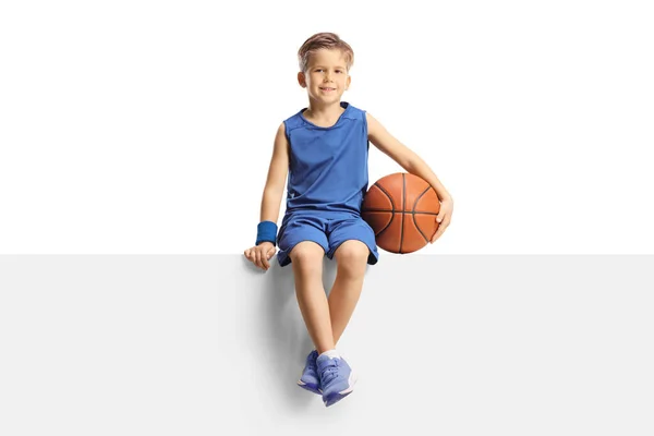 Sonriente Niño Jersey Sosteniendo Una Pelota Baloncesto Sentado Panel Blanco —  Fotos de Stock