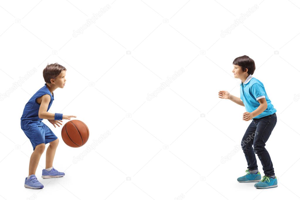 Full length profile shot of two boys playing basketball isolated on white background