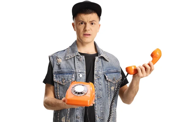 Запутавшийся Молодой Человек Держит Оранжевый Ротационный Телефон Изолирован Белом Фоне — стоковое фото