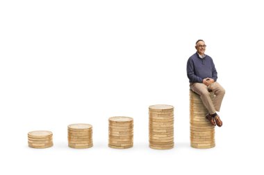 Beyaz arka planda izole edilmiş en uzun bozuk para yığınının üzerinde oturan olgun bir adam.