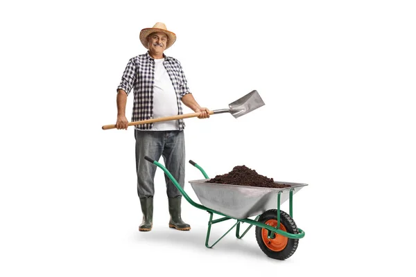 一个成熟的农民的全长肖像 他有一把铲子和满载泥土的手推车 背景是白色的 — 图库照片