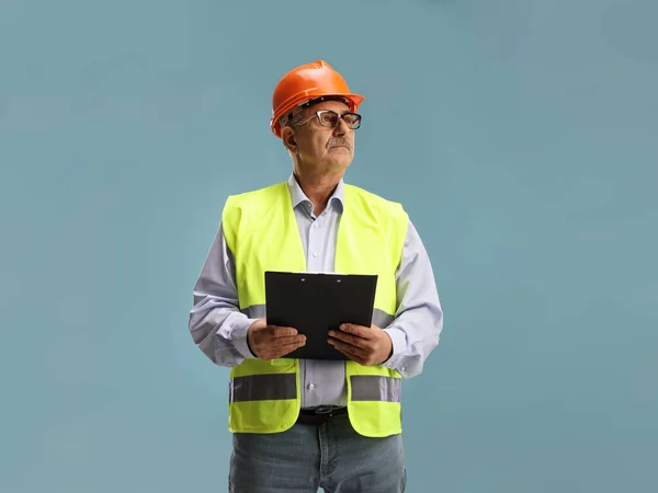 Mature Male Engineer Clipboard Safety Vest Looking Side Isolated Blue — Stock Photo, Image