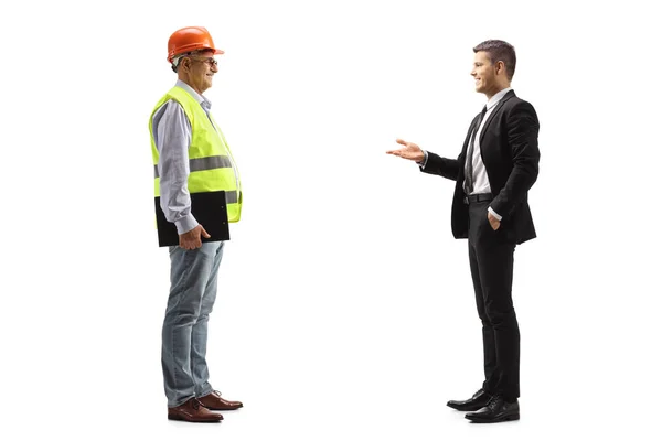 一个年轻的商人和一个有着蓝色背景的成熟的工程师交谈 — 图库照片