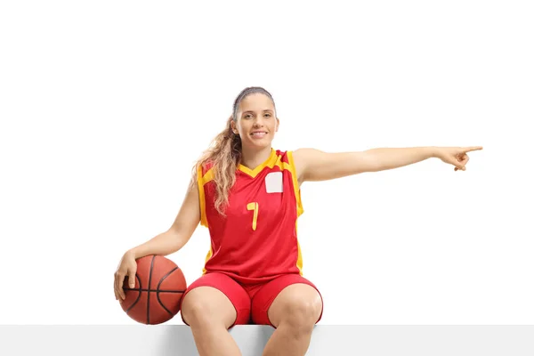 白地に隔離された側面を指す空白の板の上の女性バスケットボール選手 — ストック写真