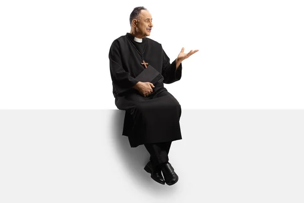 一个成熟的牧师坐在一块空白的板子上 手被白色背景隔离 摆出姿势的全景 — 图库照片