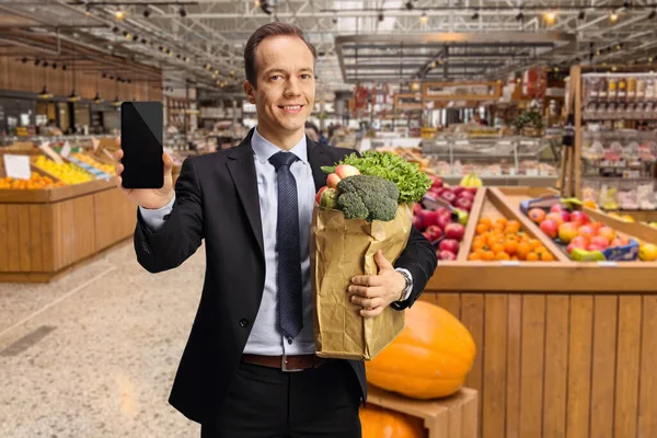 Empresario Sosteniendo Una Bolsa Papel Con Comestibles Mostrando Teléfono Inteligente — Foto de Stock