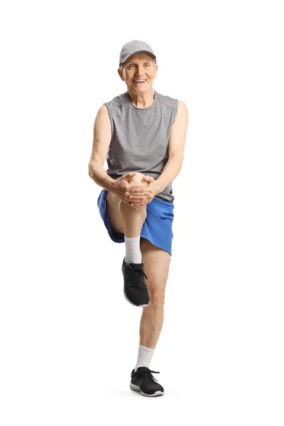 スポーツウェアの高齢者は足を伸ばし 白い背景に隔離された笑顔 — ストック写真