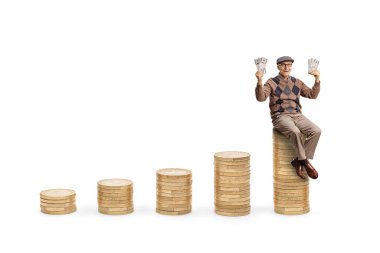 Bozuk para yığınlarının üzerinde oturan ve beyaz arka planda izole edilmiş banknotlar tutan mutlu yaşlı adam.