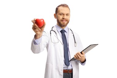 Genç bir erkek kardiyolog kırmızı bir kalp tutuyor ve beyaz arka planda izole edilmiş kameraya bakıyor.