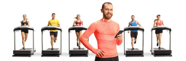 身穿运动服的男人 戴着耳机 手持智能手机 站在被白色背景隔离的跑步机上的人们面前 — 图库照片