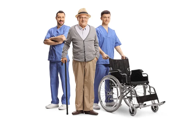 Pacjent Podeszłym Wieku Dwóch Pracowników Służby Zdrowia Wózkiem Inwalidzkim Odizolowanych — Zdjęcie stockowe