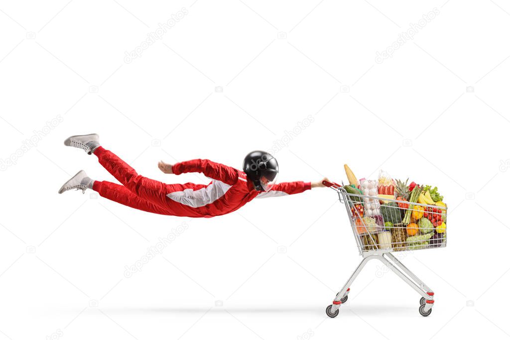 Car racer in a red suit flying and holding a shopping cart with food isolated on white background