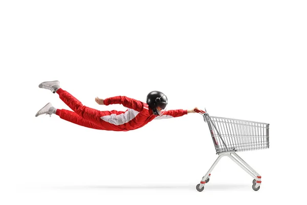 赤いスーツのカーレーサーと白い背景に隔離された空のショッピングカートで飛ぶ黒いヘルメット — ストック写真