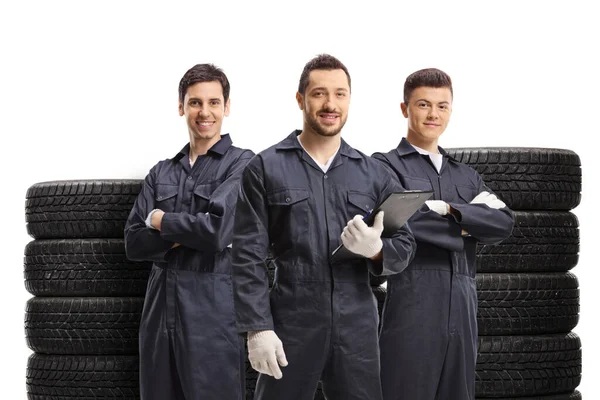 Mechanics standing with piles of tires isolated on white background