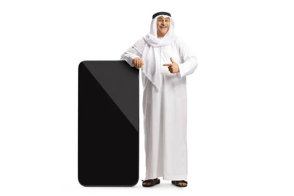 Зріла Арабська Людина Традиційному Одязі Спираючись Великий Мобільний Телефон Вказуючи — стокове фото