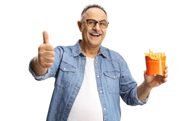 Happy Mature Man Holding French Fries Gesturing Thumb Sign Isolated — 스톡 사진
