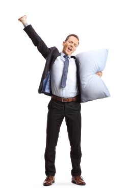 Uykulu bir iş adamının uzun bir portresi bir yastık tutuyor ve beyaz arka planda yalıtılmış bir şekilde yürüyor.