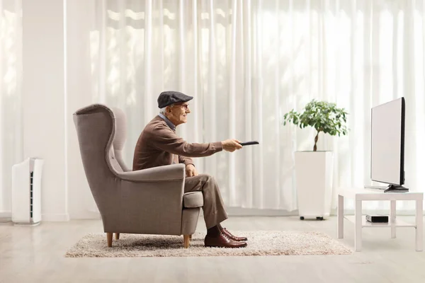 Starší Muž Křesle Přepínání Kanálů Televizi Dálkovým Ovládáním Obývacím Pokoji — Stock fotografie