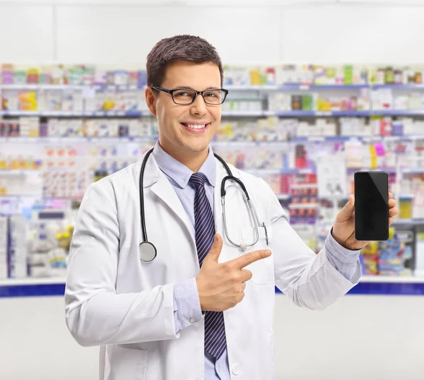 Jovem Farmacêutico Mostrando Telefone Celular Dentro Uma Farmácia — Fotografia de Stock